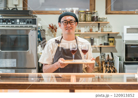 ワインバー・居酒屋・ワイナリーのキッチンで赤ワインを持つ男性カフェスタッフ 120913852