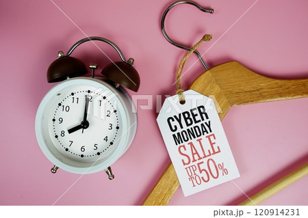 Cyber Monday Sale 50% on price tag with wooden clothes hanger and alarm clock top view on pink background 120914231