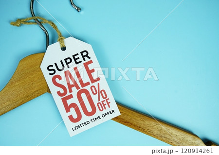 Super Sale 50% off on price tag with wooden clothes hanger top view on blue background, business and promotion concep Super Sale 50% off on price tag with wooden clothes hanger top view on blue background, business and promotion concep 120914261