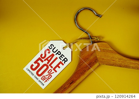 Super Sale 50% off on price tag with wooden clothes hanger top view on yellow background Super Sale 50% off on price tag with wooden clothes hanger top view on yellow background 120914264