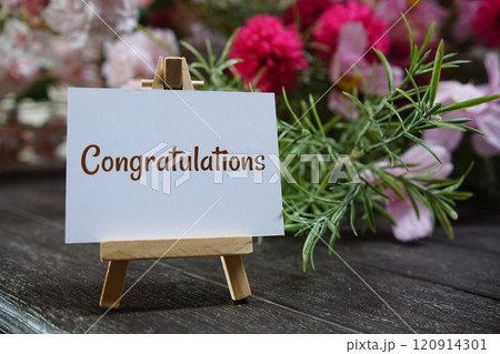 Congratulations text write on paper card with wooden easel and flowers decoration on wooden background Congratulations text write on paper card with wooden easel and flowers decoration on wooden background 120914301