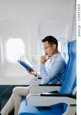 Asian male passenger of airplane sitting in comfortable seat while working laptop and tablet with mock up area using wireless connection. Travel in style, work 120921929
