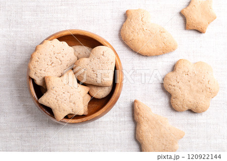 Homemade gingerbread cookies in a wooden bowl on linen fabric. Sweet, light brown and flat baked goods for Christmas season, flavored with ginger, cloves, nutmeg, cinnamon, and sweetened with honey. Homemade gingerbread cookies in a wooden bowl on linen fabric. Sweet, light brown and flat baked goods for Christmas season, flavored with ginger, cloves, nutmeg, cinnamon, and sweetened with honey. 120922144