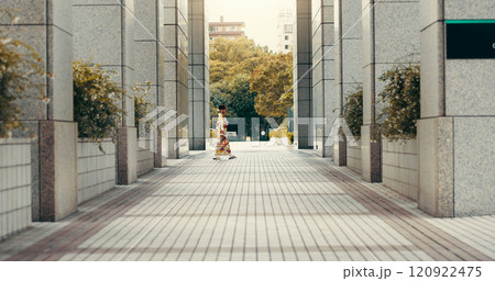 Woman, kimono and walking in city, buildings and travel with profile on urban sidewalk in summer at park. Person, outdoor and traditional fashion with style, clothes and heritage on commute in Japan 120922475