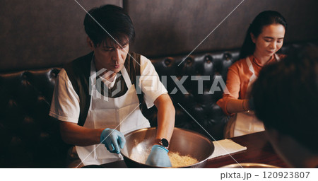 Cooking, man and woman in class with chef, romantic date and bonding together at Asian food restaurant. Couple, learning and making noodles at cafe with teacher, culinary course and Japanese culture 120923807