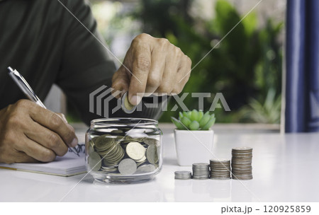 Hand with money coins in clear glass, Business investment growth concept, saving concept, Hand putting coin in clear jar. 120925859
