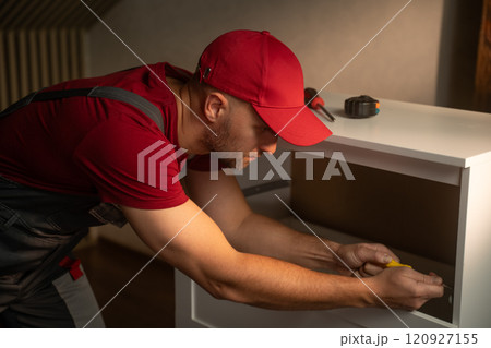Interior carpenter measures and assembles furniture in a bright home environment Interior carpenter measures and assembles furniture in a bright home environment 120927155