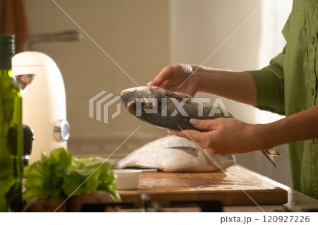 Preparing dorado fish on a baking sheet in a cozy kitchen for a delicious meal 120927226