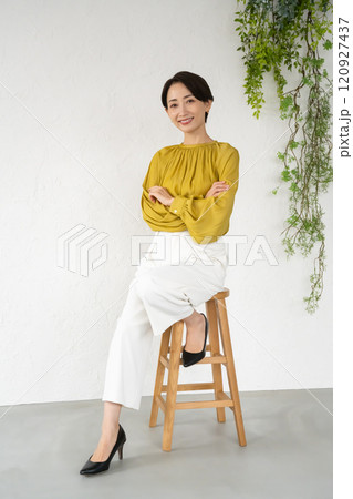 部屋で椅子に座ってポーズをとる若い女性 部屋で椅子に座ってポーズをとる若い女性 120927437