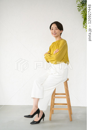 部屋で椅子に座ってポーズをとる若い女性 120927448