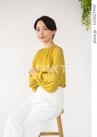 部屋で椅子に座ってポーズをとる若い女性 120927449