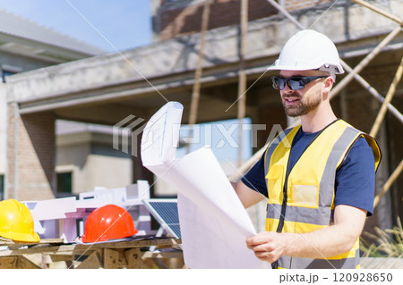Professional - senior civil engineer inspecting or working in construction site, contractor examining a building blueprint or layout on paper. 120928650