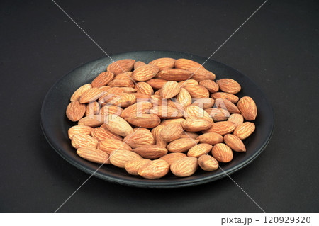 Black plate full of Fresh almonds in black background 120929320