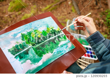 Artistic creation of a green forest and lake scene using watercolors during outdoor painting Artistic creation of a green forest and lake scene using watercolors during outdoor painting 120930203