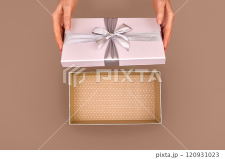 Woman opening empty pink gift box silver ribbon bow Mocha Mousse background 120931023