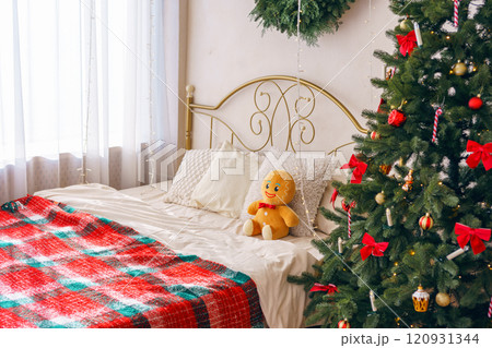 Festive bedroom, cozy bed with gingerbread plush toy, decorative pillows and Christmas tree 120931344
