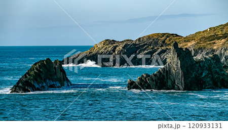 A view of a rocky coastline with a blue ocean. The water is a deep blue in color. A view of a rocky coastline with a blue ocean. The water is a deep blue in color. 120933131