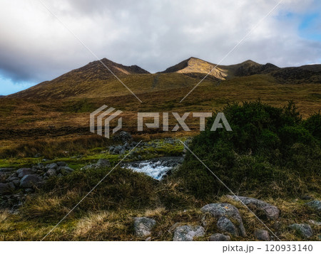 A stunning view of rugged mountains bathed in soft sunlight contrasts with a clear blue sky. A gentle stream winds through the rocky terrain, enhancing the peaceful atmosphere. A stunning view of rugged mountains bathed in soft sunlight contrasts with a clear blue sky. A gentle stream winds through the rocky terrain, enhancing the peaceful atmosphere. 120933140