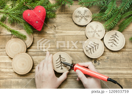 Christmas or New Year homemade pyrography toys. Wooden slice. Alternative decor. Christmas decorations. Child makes gifts for relatives. View from above. 120933759