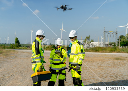 Wind turbine or windmill worker woman or technician control drone to work with her co-worker team in workplace field during day time. 120933889