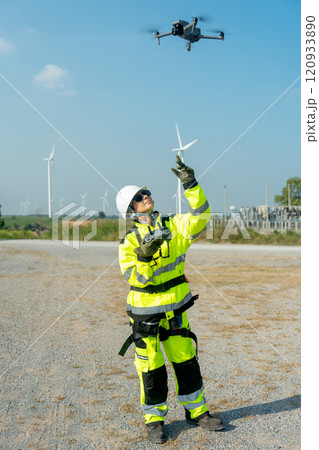 Vertical image wind turbine or windmill worker woman or technician control drone to work in workplace field during day time. Vertical image wind turbine or windmill worker woman or technician control drone to work in workplace field during day time. 120933890