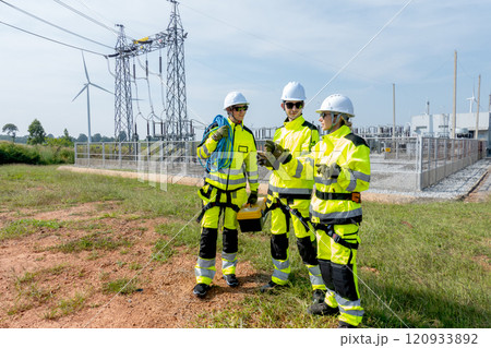 Wide shot of wind turbine or windmill workers or engineer stay in front of small electricity or power plant and discuss with mobile phone and wind turbine as background. Wide shot of wind turbine or windmill workers or engineer stay in front of small electricity or power plant and discuss with mobile phone and wind turbine as background. 120933892
