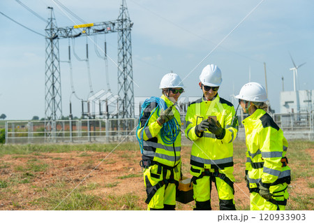 Wind turbine or windmill workers or engineer stay in front of small electricity or power plant and discuss with mobile phone and wind turbine as background. 120933903