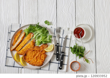 Pork Milanese with lettuce and lemon on a plate 120933952