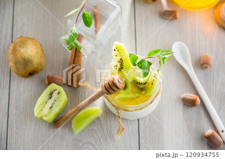 Homemade yogurt in a glass jar with honey, kiwi, nuts. 120934755