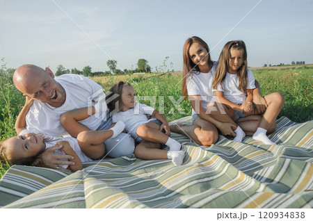 Happy family on a summer walk, mother, father and child walk in the field and enjoy the beautiful nature, at sunset. 120934838