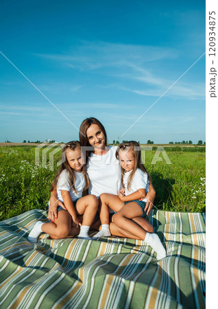 Smiling mother in a white dress enjoying time with little daughter in summer day. Smiling mother in a white dress enjoying time with little daughter in summer day. 120934875