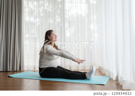 Gen Z pregnant woman practicing yoga at home. Stretching exercise. Expectant mother doing prenatal training class. Gen Z pregnant woman practicing yoga at home. Stretching exercise. Expectant mother doing prenatal training class. 120934932