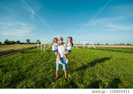 Dad having fun with pretty daughters in nature on sunset. 120935451