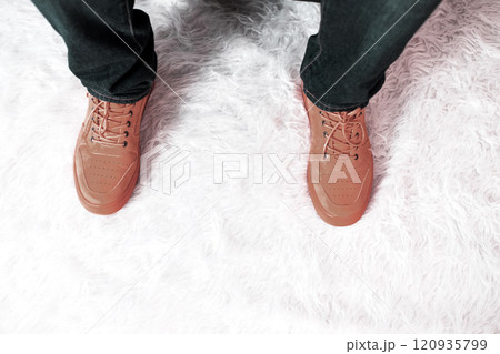 Anonymous person in brown sneakers on fluffy carpet. Trendy colors of the year 120935799