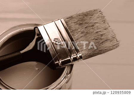 Paintbrush balanced on a can, showcasing the warm tone of paint 120935809
