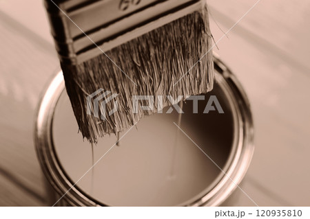 Close-up of paintbrush dipped in a can on wooden surface 120935810