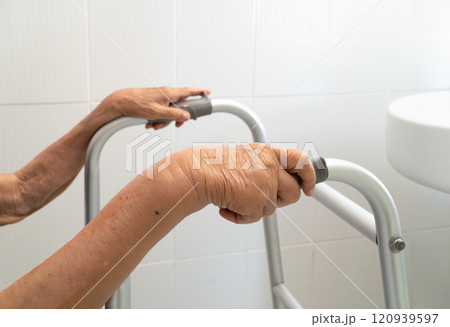 Elderly woman holding on walker in toilet. 120939597