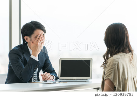 弁護士事務所・個別相談会でトラブルの相談をする相談者女性と男性弁護士・相談員（落ち込む・困る・悩む） 120939783