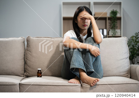 woman sit Depression Dark haired  pensive glance Standing by window on sofa and anxiety 120940414