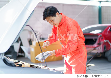 Professional automobile technician inspects customer's vehicle liquid system and engine oil level. Technician working in garage. Professional automobile technician inspects customer's vehicle liquid system and engine oil level. Technician working in garage. 120943097