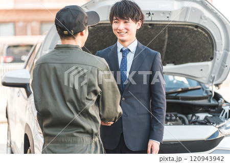 ロードサービスを受けて整備士と握手するドライバーの若い男性 120943942