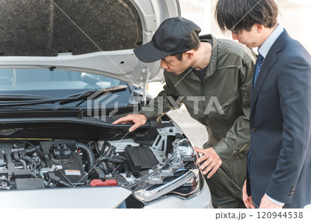 自動車のエンジンルームでドライバーに説明する整備士の男性スタッフ 120944538