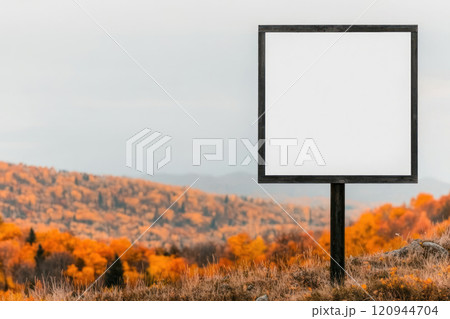 blank vertical billboard stands on hillside surrounded by vibrant autumn foliage, creating serene 120944704