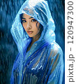 雨の中でレインコート着て立っている東洋系の女性 120947300