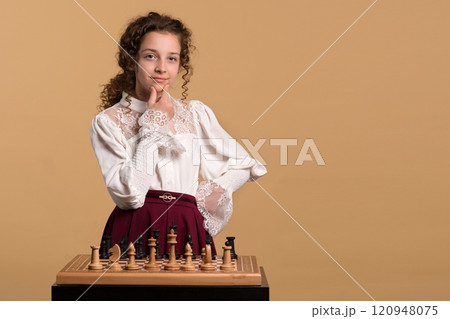 Young girl confidently smiling while considering chess move. Young girl confidently smiling while considering chess move. 120948075
