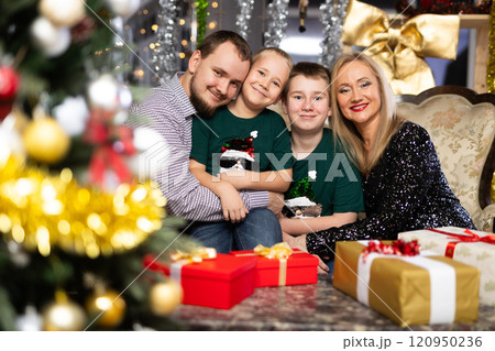 Portrait of happy family with two children celebrating Christmas next to Christmas tree Portrait of happy family with two children celebrating Christmas next to Christmas tree 120950236