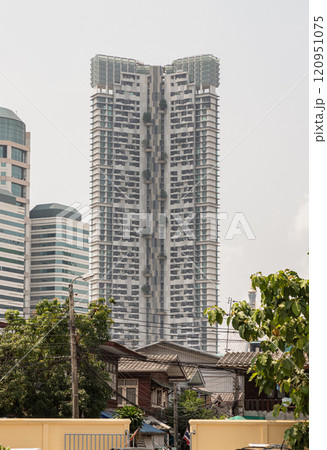 An old wooden Thai house style with Modern tall condominium building and sky in the background. An old wooden Thai house style with Modern tall condominium building and sky in the background. 120951075