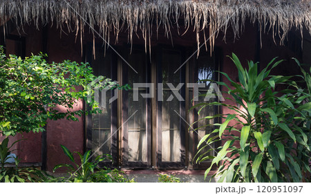 Side view of Stunning wooden house with Glass windows and Thatched roof. Side view of Stunning wooden house with Glass windows and Thatched roof. 120951097