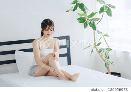 ベッドで脚のスキンケアをする女性 120956978