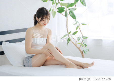 ベッドで脚のスキンケアをする女性 120956980